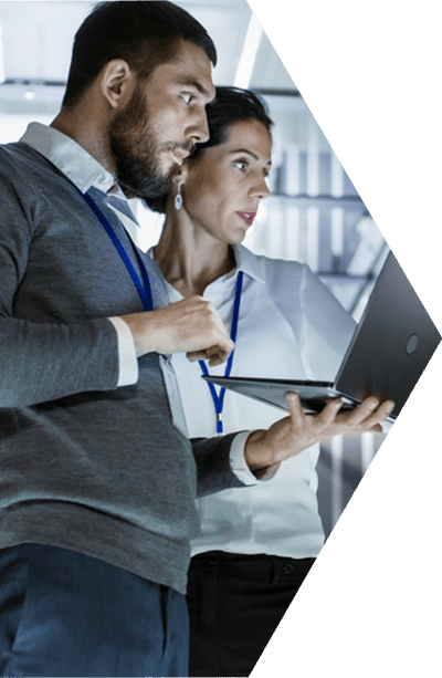 A businessman and business woman standing side by side and looking at a laptop.