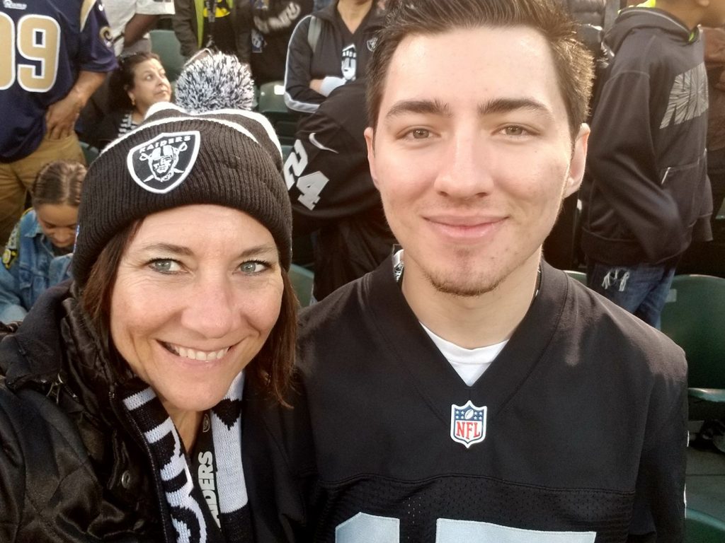 Photo of Christie Fisher in Raiders gear with her son sitting to the right of her in the photo