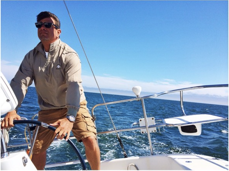 A photo of David Bristow on a sailboat with a blue sky in the background